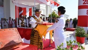 Bupati Kupang Yosef Lede menyerahkan Bendera Merah Putih kepada petugas pembawa baki dalam upacara pengibaran Bendera Merah Putih ini adalah Ni Made Widya Sriadi Dwi Jayanti, asal SMA Negeri 1 Kupang Timur, Minggu. Foto Prokopim Setda Kabupaten Kupang.