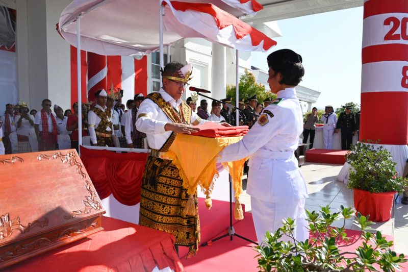 Bupati Kupang Yosef Lede menyerahkan Bendera Merah Putih kepada petugas pembawa baki dalam upacara pengibaran Bendera Merah Putih ini adalah Ni Made Widya Sriadi Dwi Jayanti, asal SMA Negeri 1 Kupang Timur, Minggu. Foto Prokopim Setda Kabupaten Kupang.