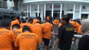 Polisi menggiring puluhan tersangka yang terjaring gerebekan dalam "LGBT Siwalan Party" menuju ke ruang tahanan di Polrestabes Surabaya, Rabu (22/10/2025). foto ant