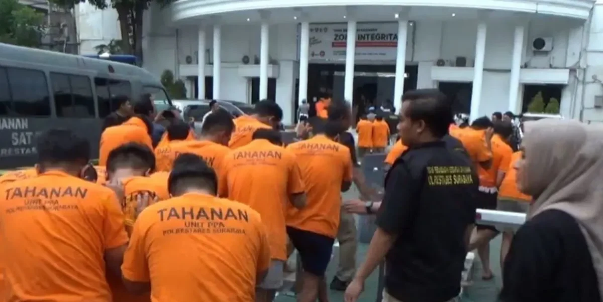 Polisi menggiring puluhan tersangka yang terjaring gerebekan dalam "LGBT Siwalan Party" menuju ke ruang tahanan di Polrestabes Surabaya, Rabu (22/10/2025). foto ant